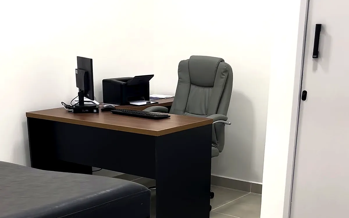 Consultório da unidade do KM 32, com mesa de atendimento e maca